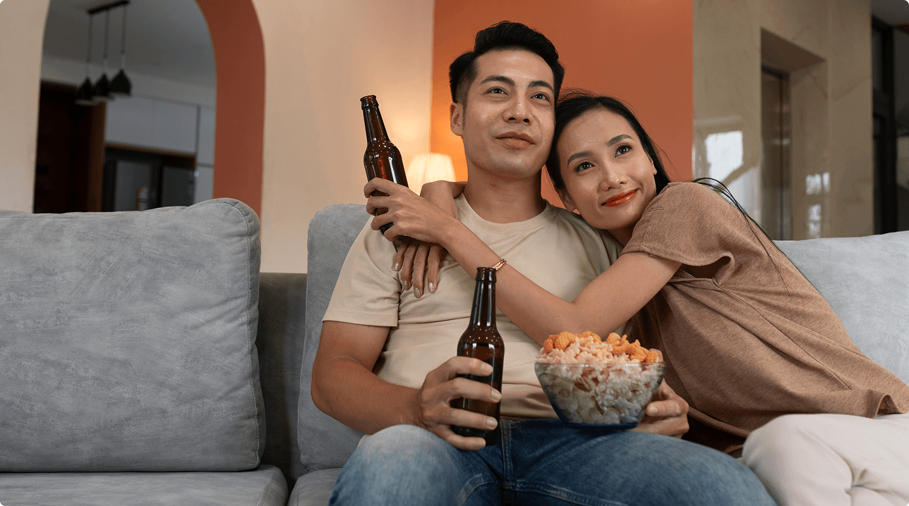 Couple enjoying movie night with drinks and popcorn